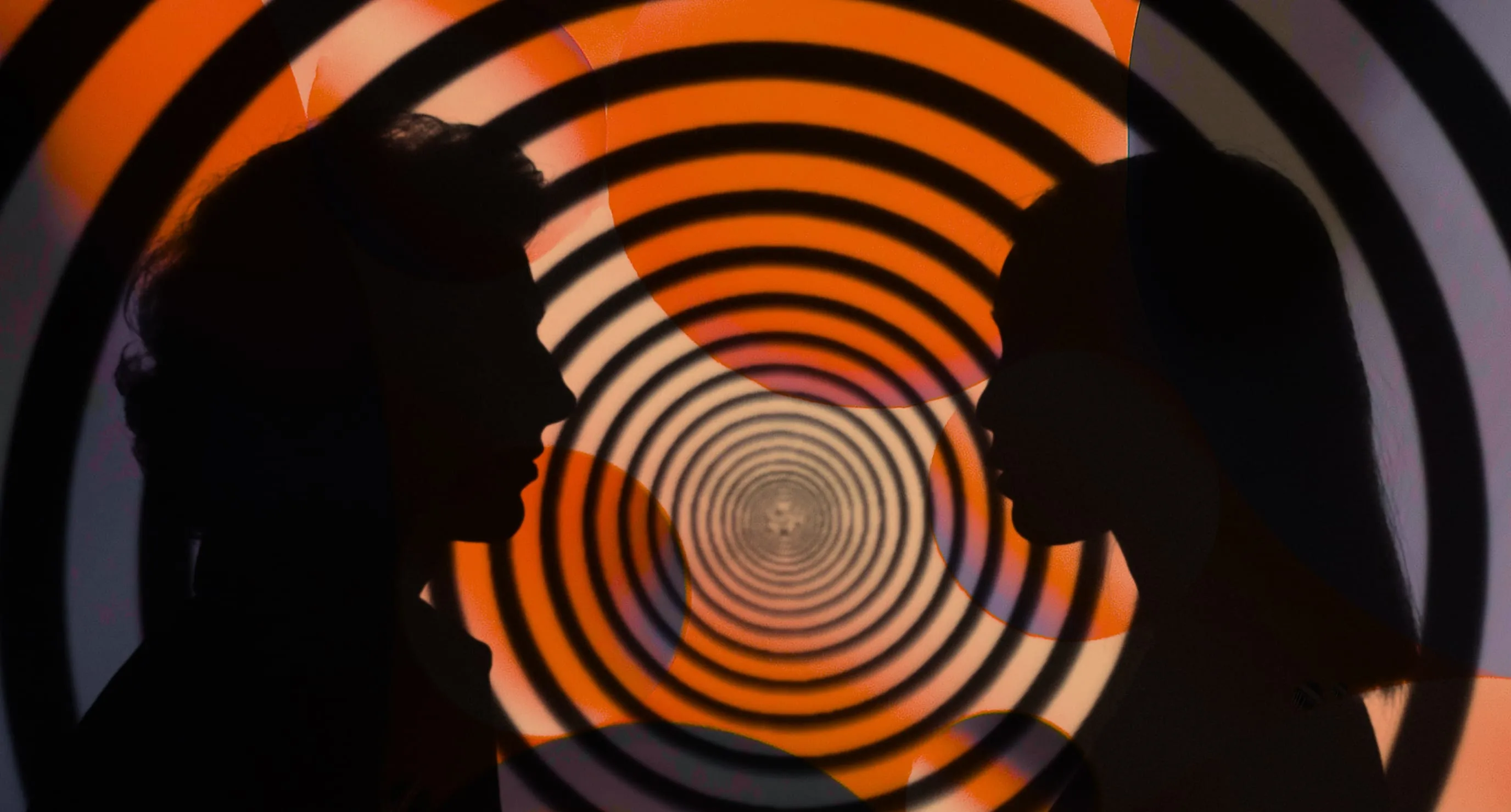 Two silhouettes facing each other with circular patterned background.